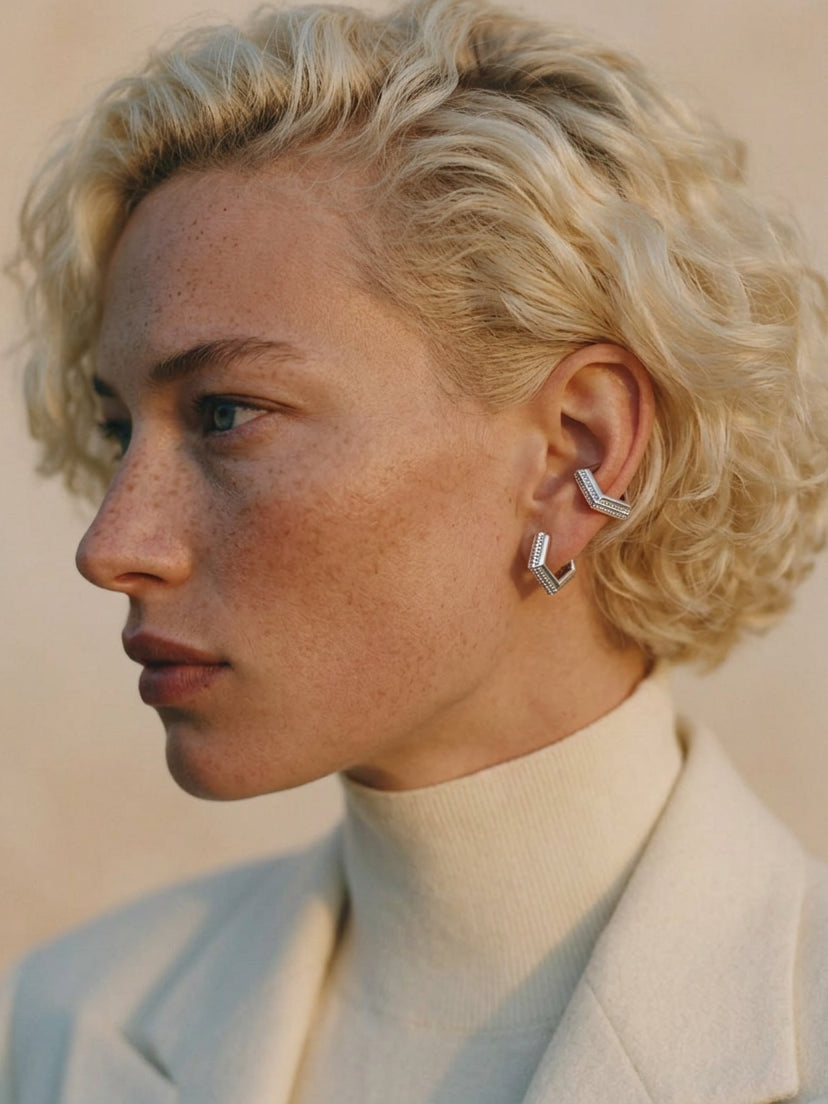 Model wearing Mini Verta Earrings and an ear cuff, cream turtleneck and jacket
