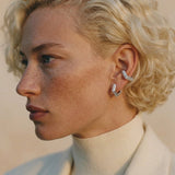 Model wearing Mini Verta Earrings and an ear cuff, cream turtleneck and jacket