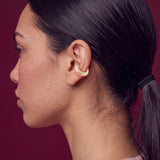 Blush Serenity 14K gold-plated ear cuff on a model in a pink sweater, profile view