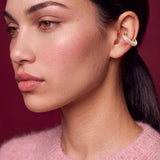 Blush Serenity gold-plated ear cuff with powder pink enamel, model in a pink sweater on a burgundy backdrop