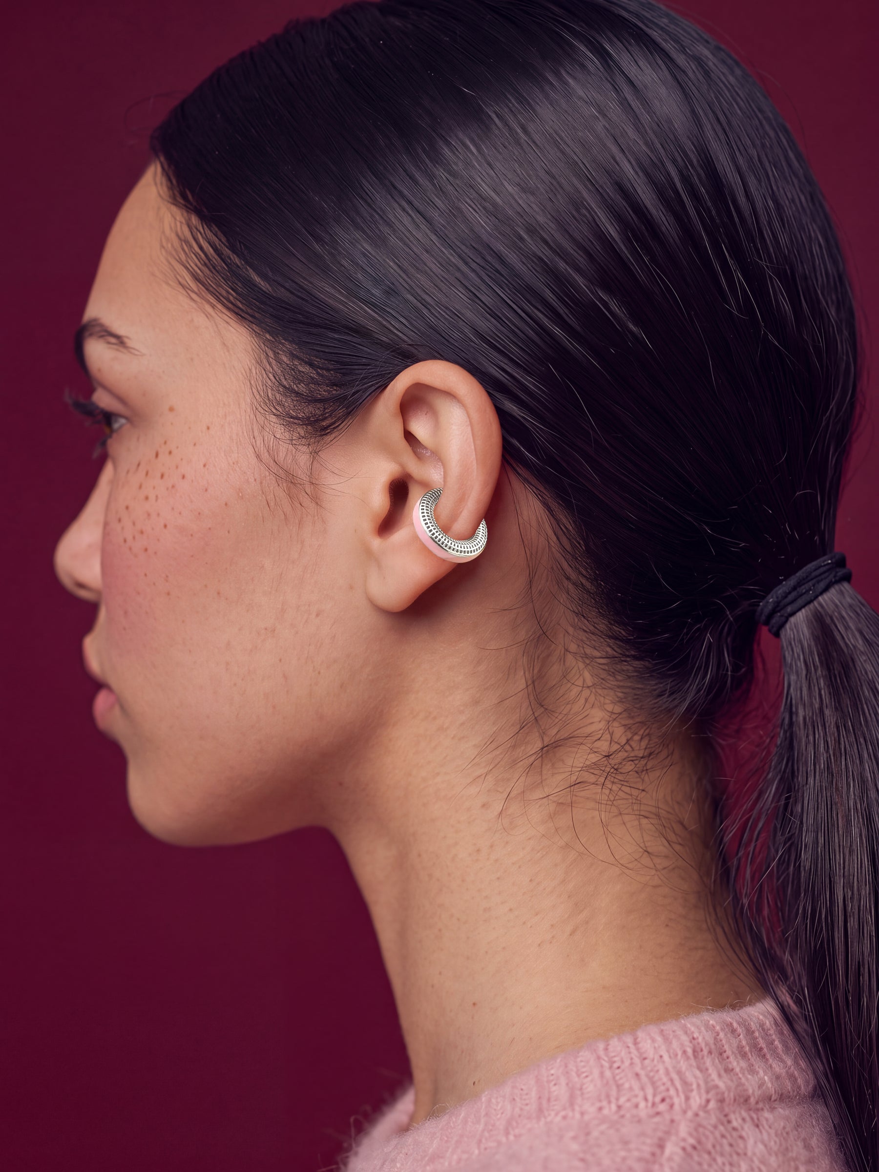 Blush Serenity rhodium-plated ear cuff on a model in a pink sweater, profile view