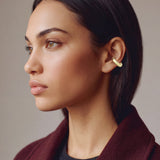 Hola Aura gold-plated ear cuff on a model in a burgundy coat, profile view