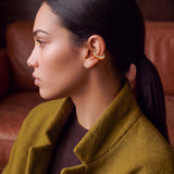 Ignite Pulse 14K gold-plated ear cuff on a model in an olive coat, profile view