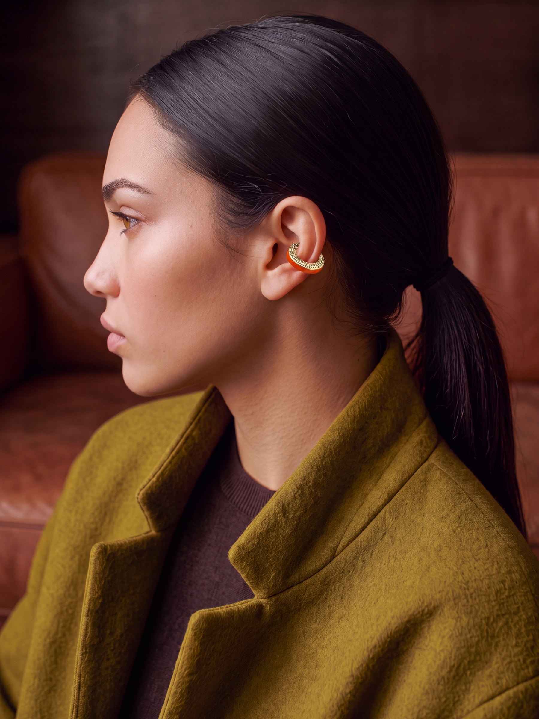 Ignite Pulse 14K gold-plated ear cuff on a model in an olive coat, profile view