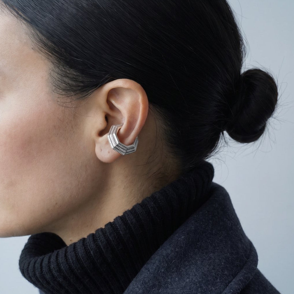 Model wearing the Octa Ear Cuff with a charcoal wool coat and black turtleneck, editorial shot