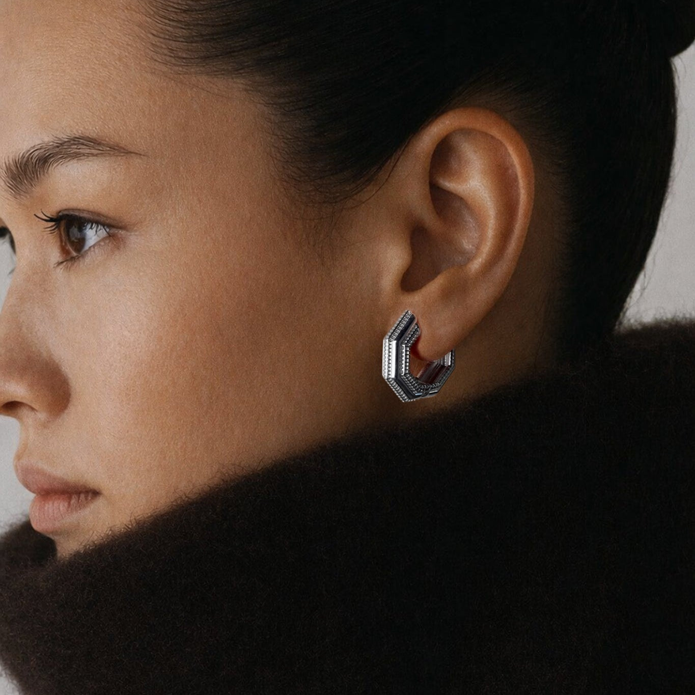 Model wearing Octa Earrings in profile, dark brown fur collar
