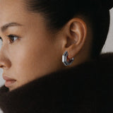 Model wearing Octa Earrings in profile, dark brown fur collar