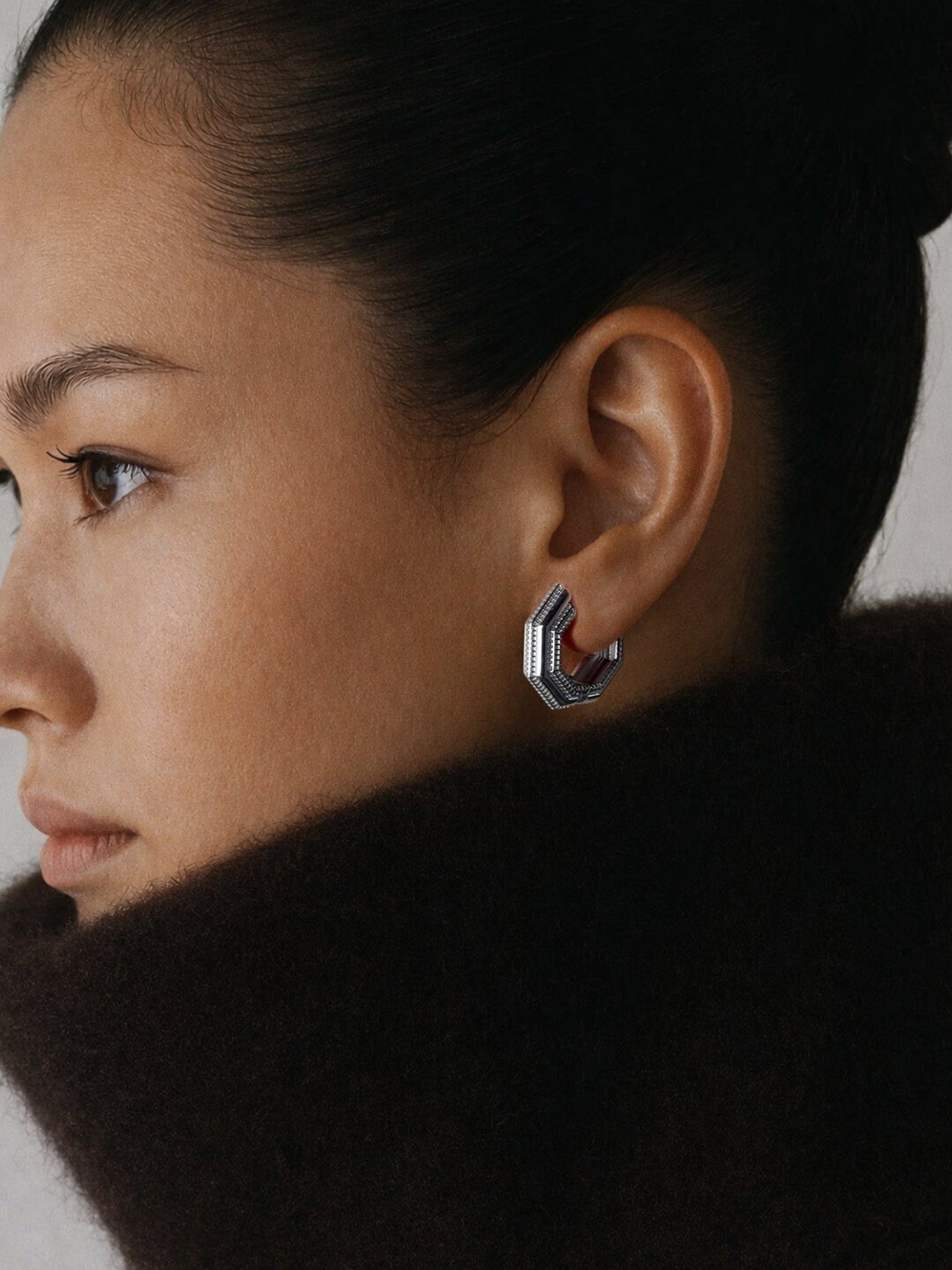 Model wearing Octa Earrings in profile, dark brown fur collar