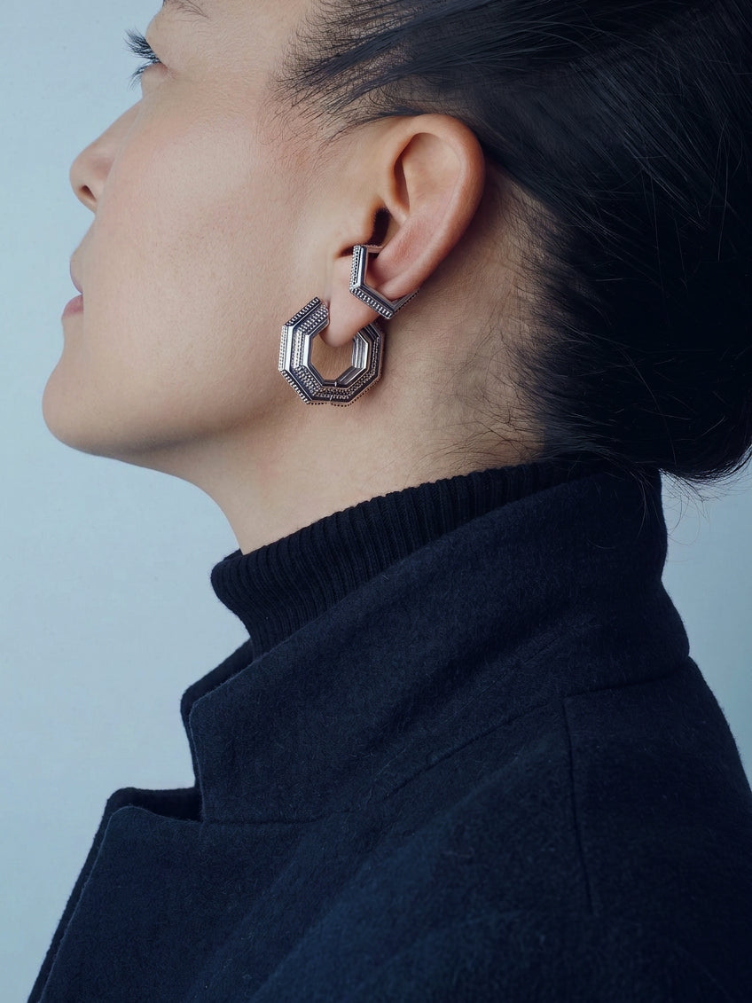 Front view of the Octavia octagonal silver hoop styled with an ear cuff and a black turtleneck