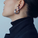 Front view of the Octavia octagonal silver hoop styled with an ear cuff and a black turtleneck