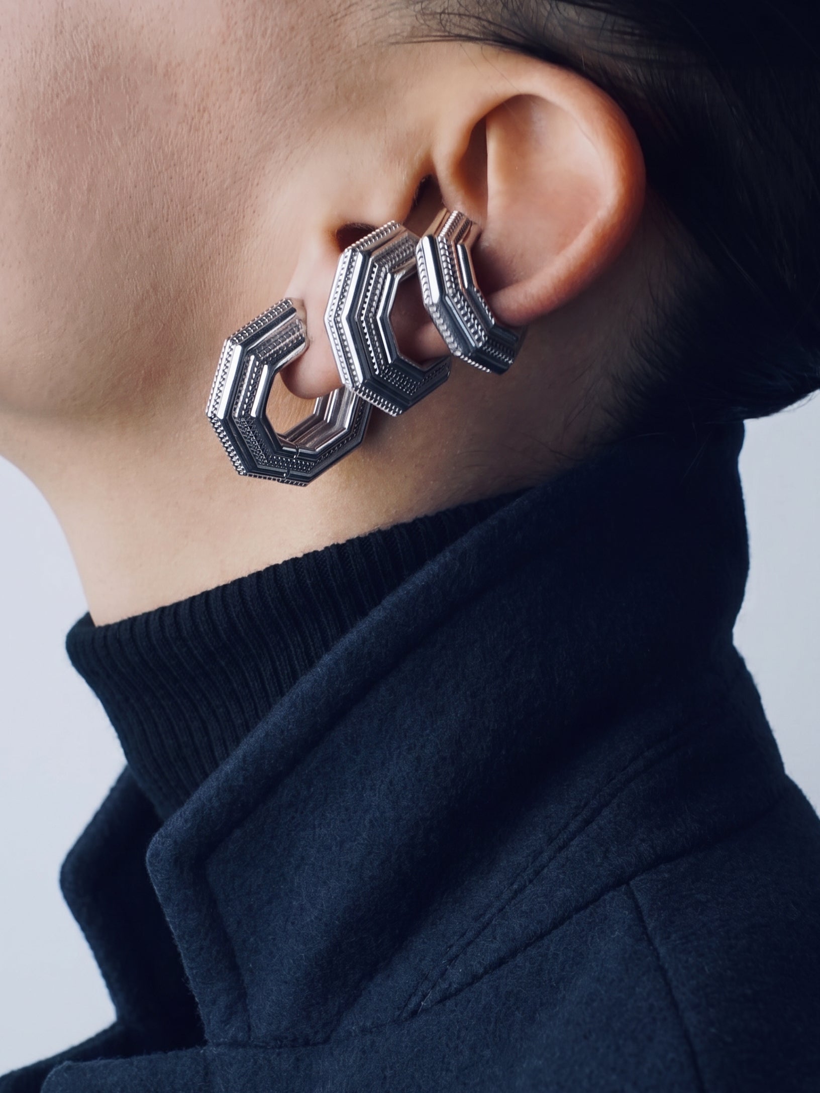 Octavia earring stacked with two UNBOUND ear cuffs, navy coat