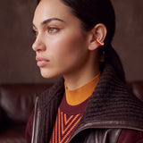 Scarlet Pulse gold-plated ear cuff with red enamel on a model in a leather jacket and burgundy knit