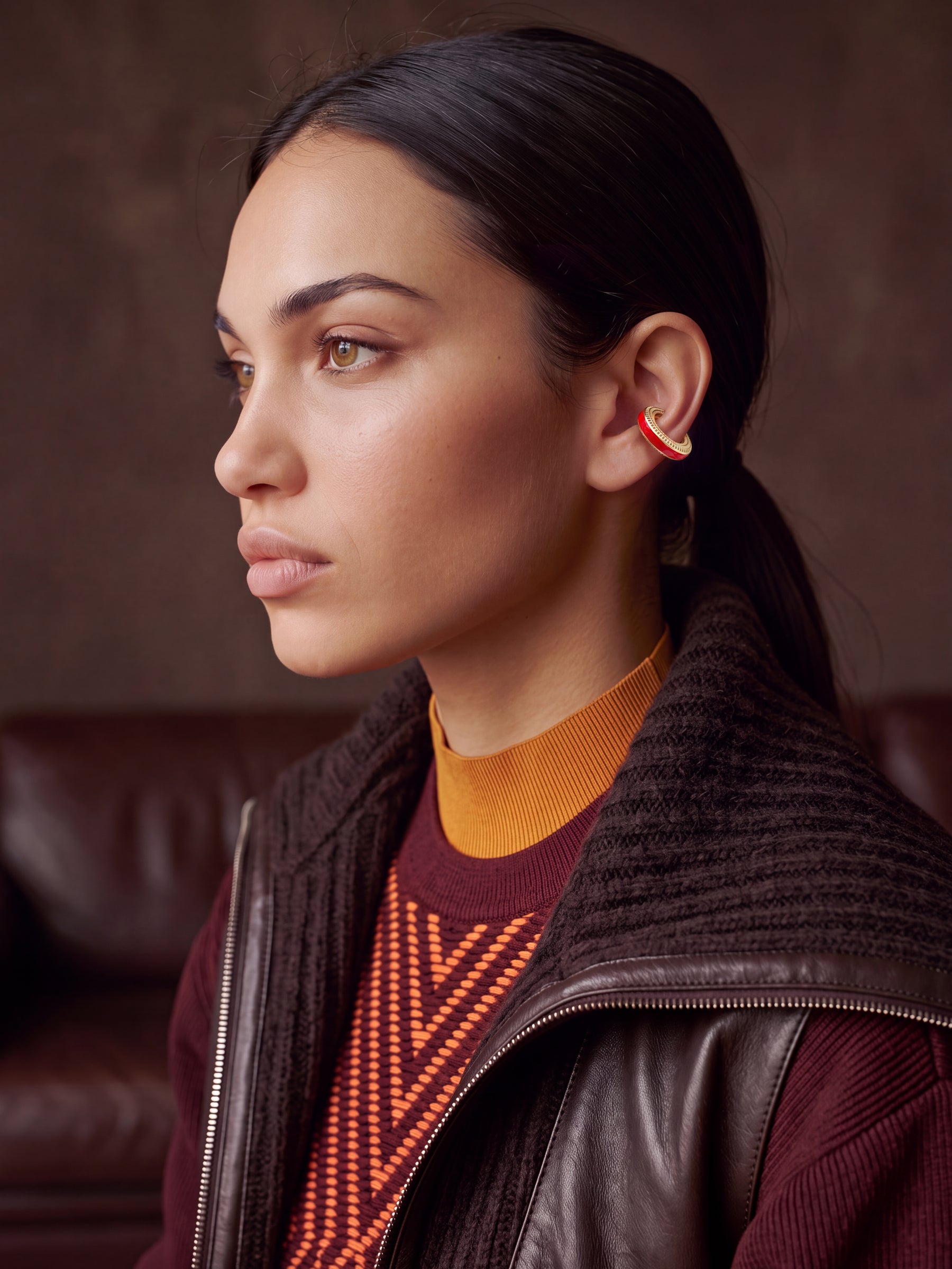 Scarlet Pulse gold-plated ear cuff with red enamel on a model in a leather jacket and burgundy knit