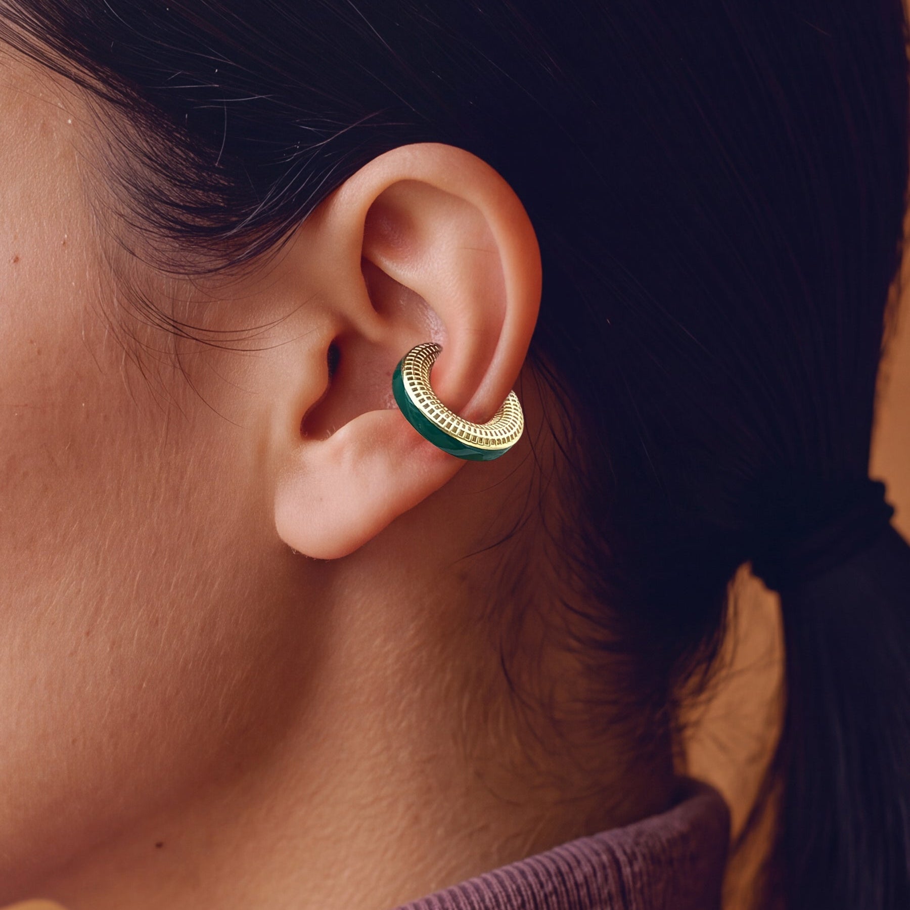 Verdant Poise 14K gold-plated ear cuff with green enamel, close-up on the ear