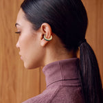 Verdant Poise gold-plated ear cuff on a model with a sleek ponytail, back view