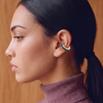 Model wearing the Verdant Poise silver ear cuff with green enamel and a plum turtleneck, profile view