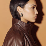 Verdant Poise green enamel silver earring, profile view of a model in a brown leather jacket